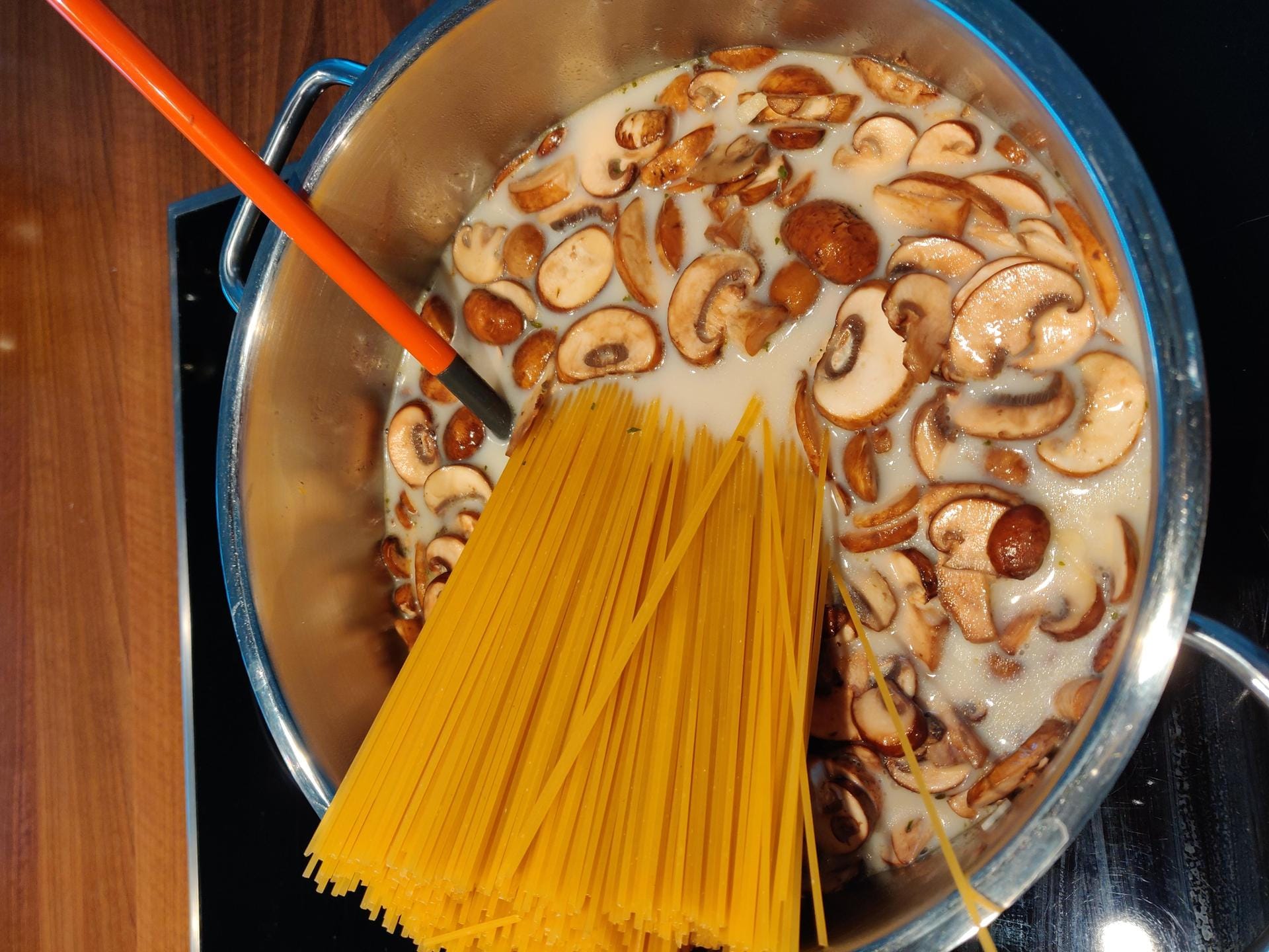 Geben Sie nun einfach die rohen Spaghetti dazu und gießen Sie das Ganze mit der Gemüsebrühe und Milch auf. Lassen Sie alles auf mittlerer Hitze köcheln. Drücken Sie die Nudeln – sobald sie weicher werden – in den Topf, damit alle Spaghetti mit Flüssigkeit bedeckt werden.