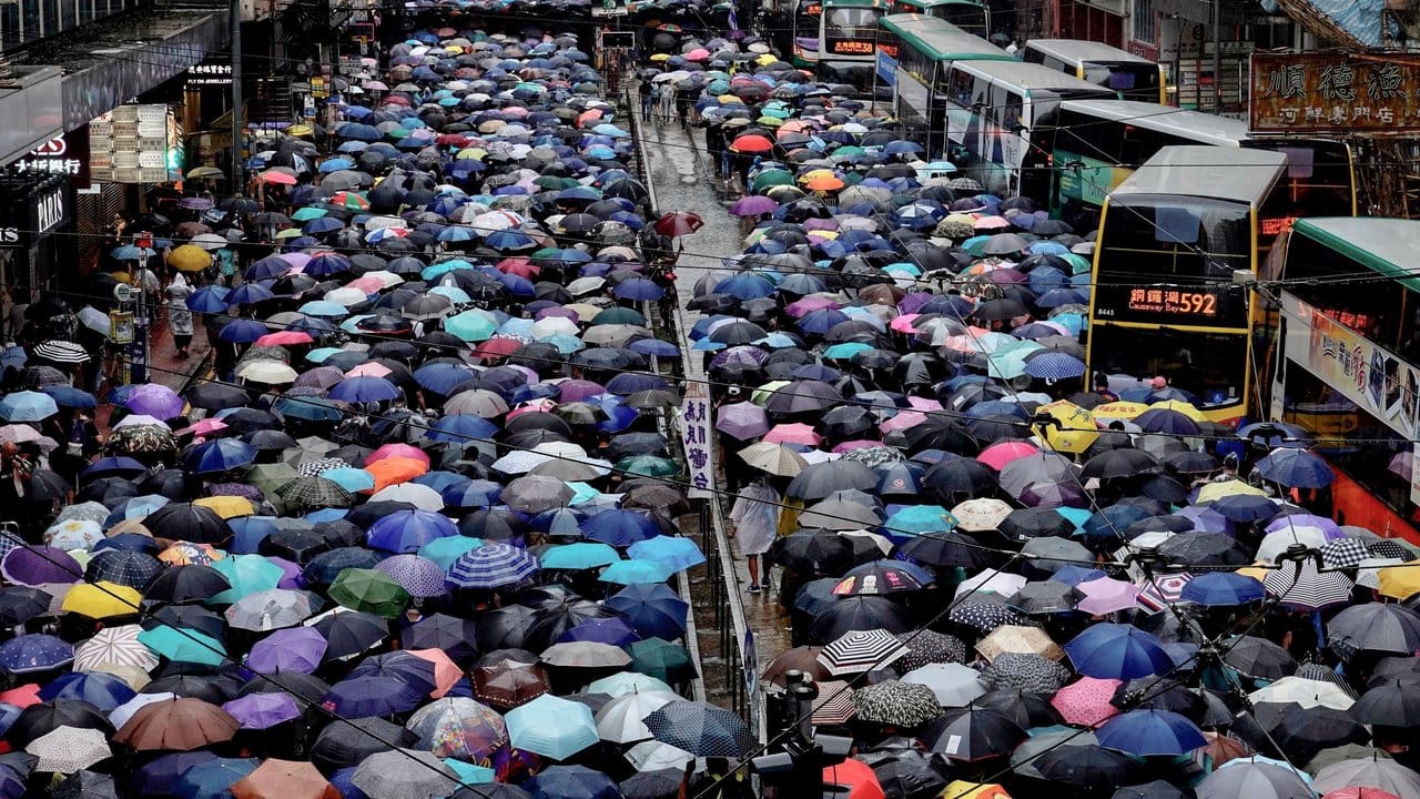 Regierungsfeindliche Demonstranten mit Regenschirmen nehmen an einem Marsch teil und beeinträchtigen damit den Verkehr.