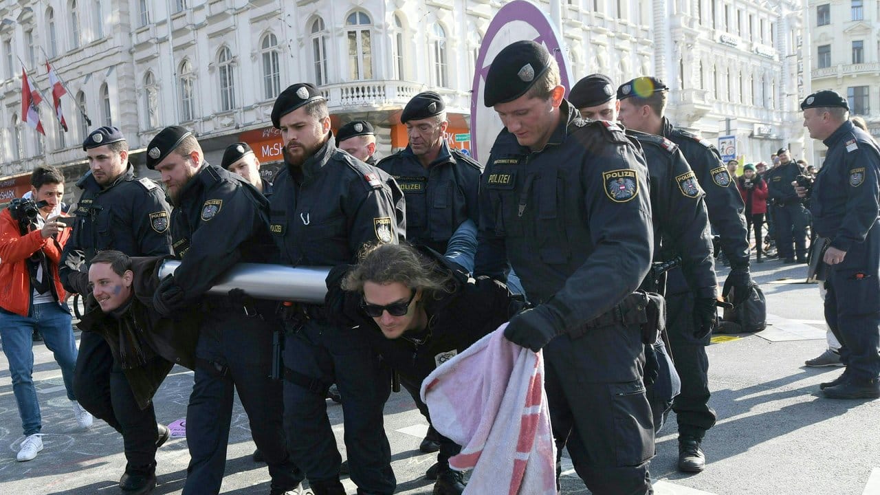Aktivisten werden in Wien von Polizisten weggetragen.