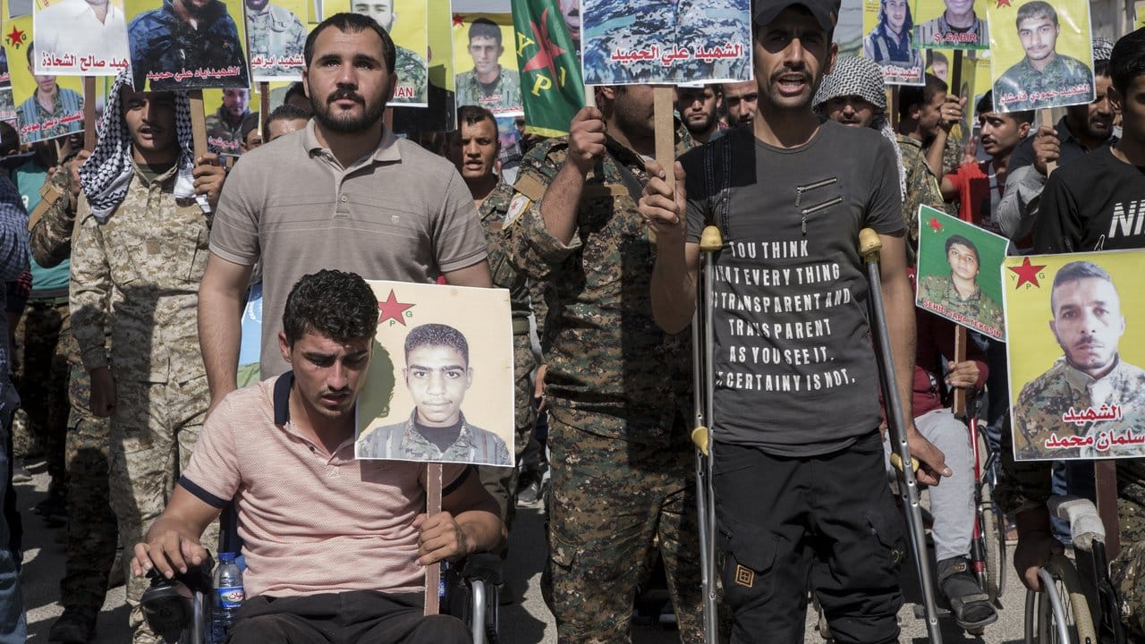 Verwundete kurdische Kämpfer präsentieren im nordostsyrischen Qamischli Bilder von Kameraden, die im Kampf gegen den IS getötet wurden.