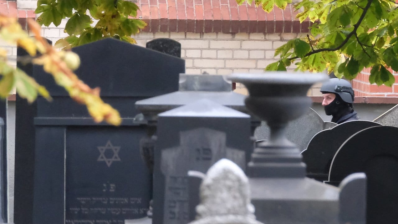 Ein Polizist mit Schutzhelm steht zwischen Grabsteinen auf dem jüdischen Friedhof von Halle. Ein Polizist mit Schutzhelm steht zwischen Grabsteinen auf dem jüdischen Friedhof von Halle.