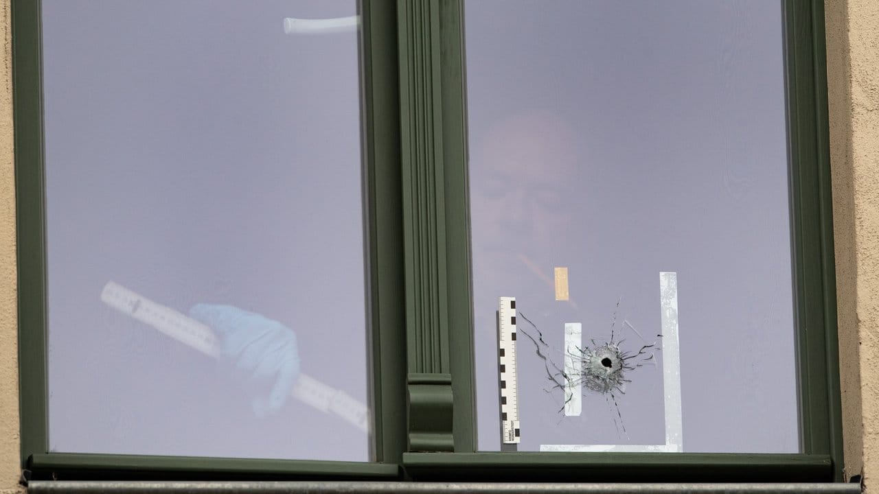 Ein Beamter der Spurensicherung untersucht das Loch in einem Fenster in einem Haus gegenüber der Synagoge.