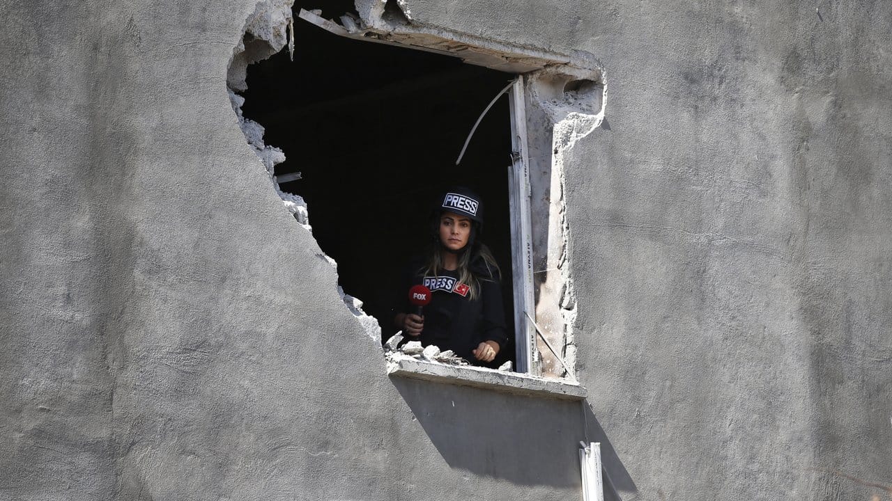 Eine Journalistin schaut aus einem Loch in der Wand eines Hauses in Akçakale, das von einem Mörser aus Syrien beschädigt wurde.