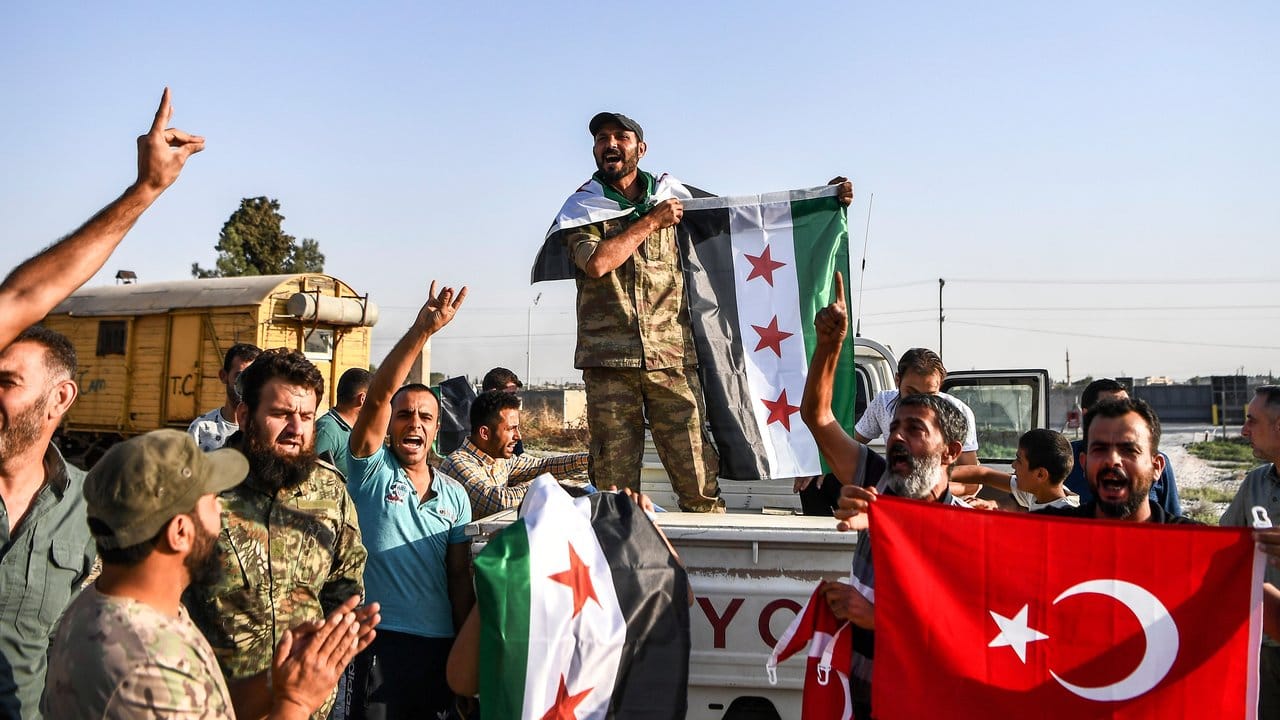Syrische Oppositionskämpfer, die von der Türkei unterstützt werden, jubeln im türkischen Grenzort Akcakale.