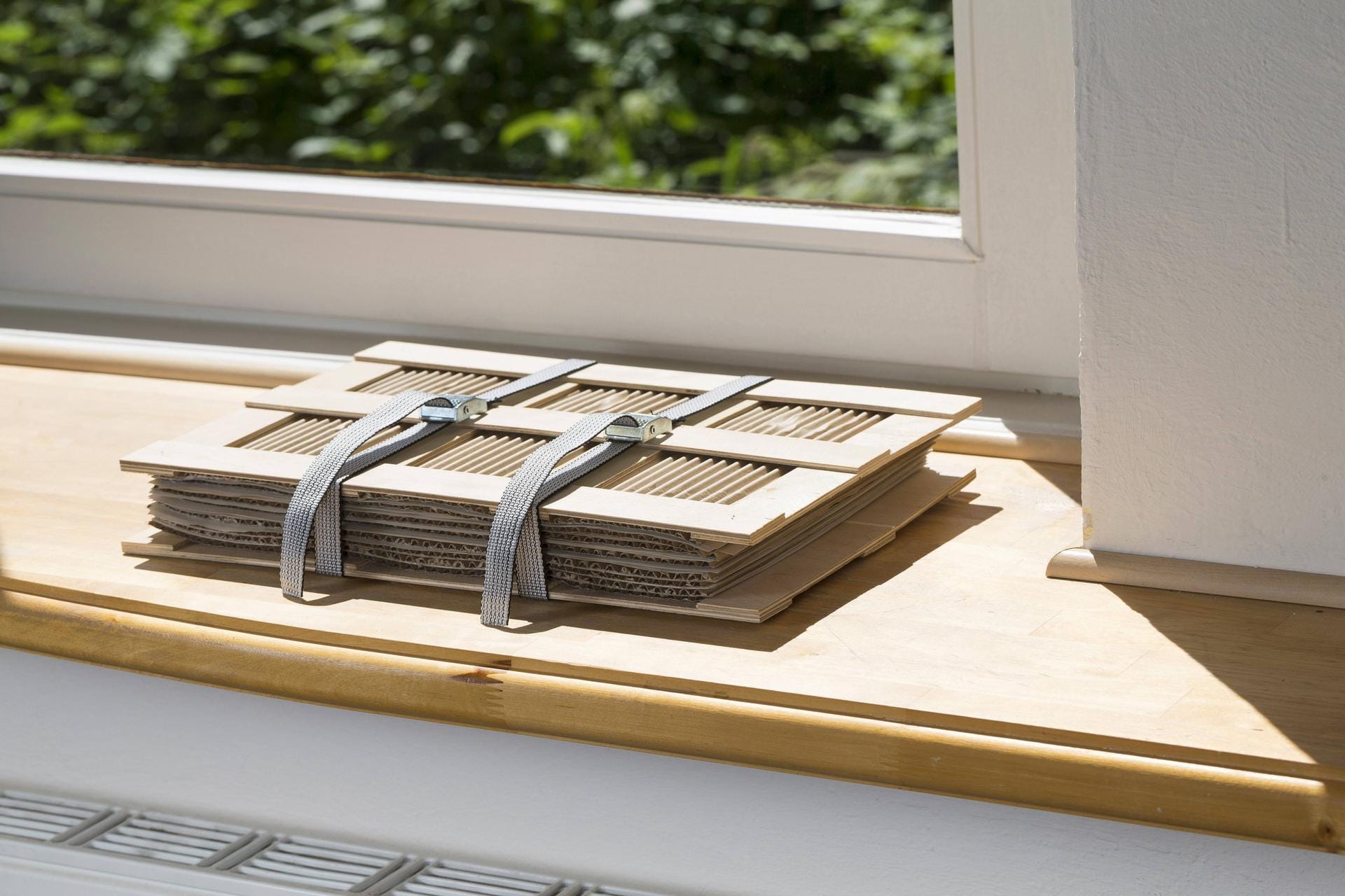 Pflanzenpresse liegt auf Fensterbank: Damit die Blätter schneller trocknen, legen Sie die Presse an einen sonnigen Ort oder auf die Heizung.