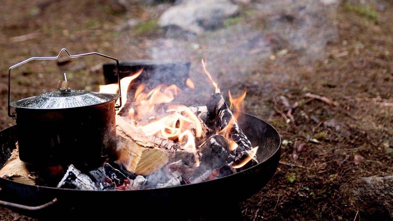 Die Töpfe und Pfannen des Waldmenüs kommen direkt auf die brennenden Holzscheite der Feuerschalen.