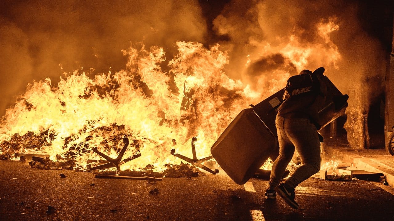 Ein Demonstrant wirft einen Mülleimer auf eine brennende Barrikade bei Protesten gegen die Verurteilung katalanischer Separatistenführer.