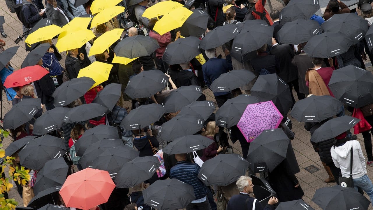 Mit Regenschirmen beteiligen sich zahlreiche Menschen auf der Buchmesse an einer Mahnwache für die Meinungsfreiheit.