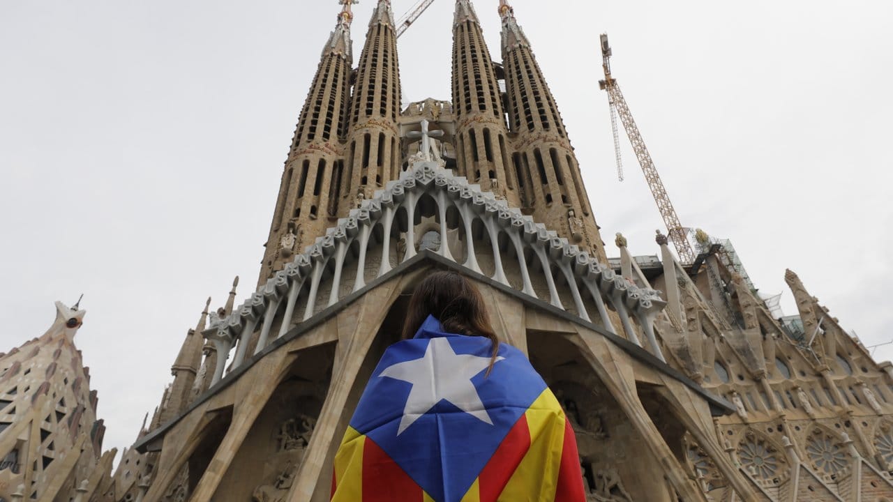 Eine Demonstrantin steht vor Barcelonas Wahrzeichen, der Sagrada Familia.