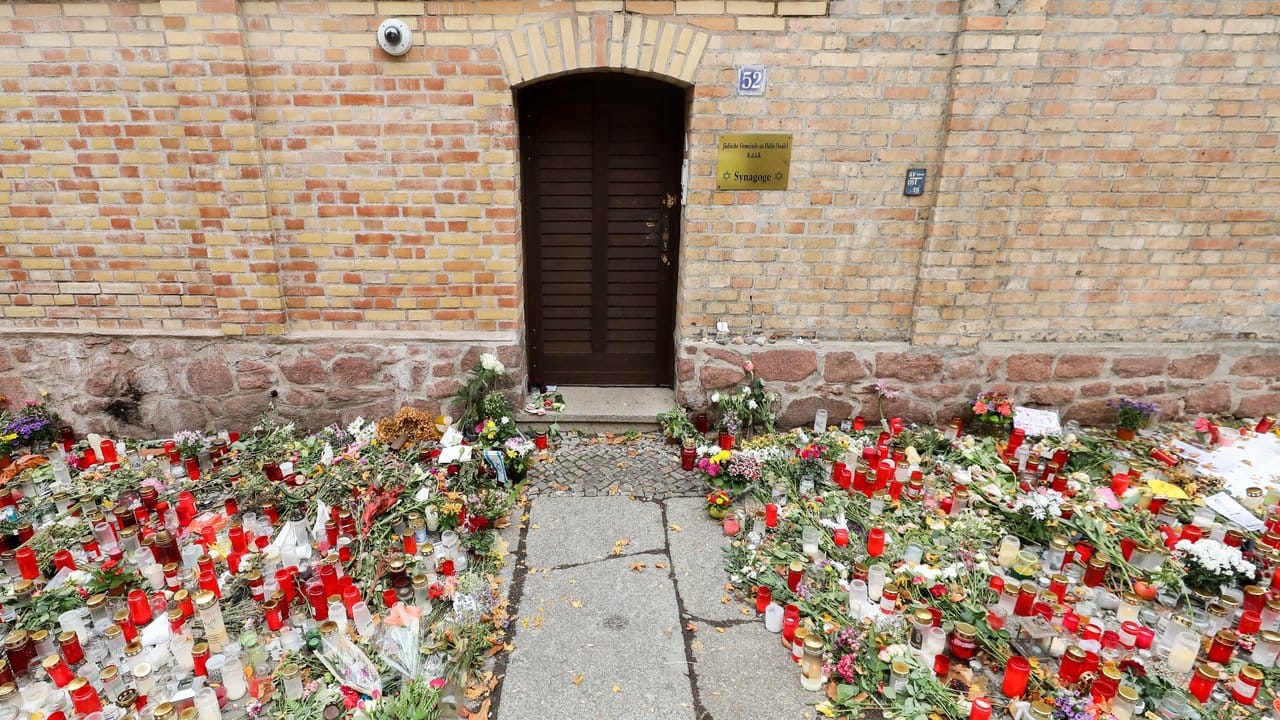 Nur noch ein schmaler Weg führt zwischen den Blumen und Kerzen zur Tür der Synagoge Halle.
