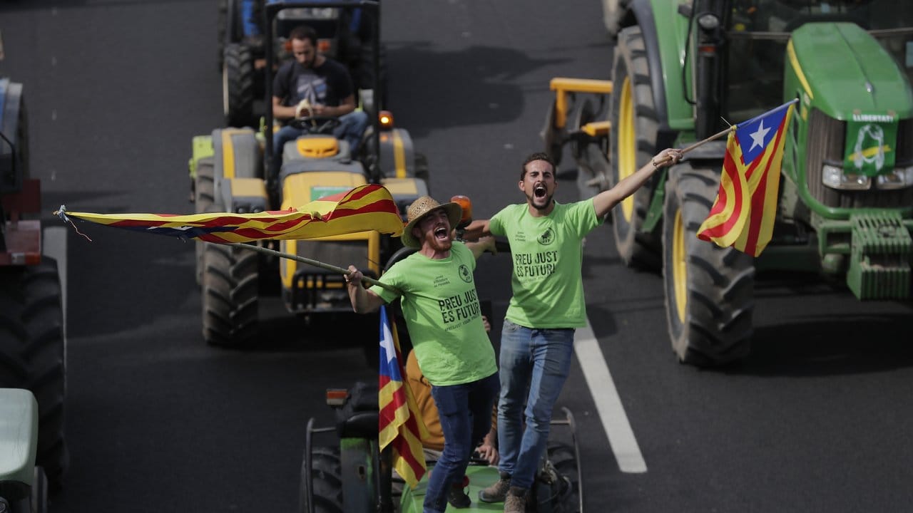 Demonstranten stehen auf einem Traktor und schwenken katalanische Fahnen. Demonstranten stehen auf einem Traktor und schwenken katalanische Fahnen.