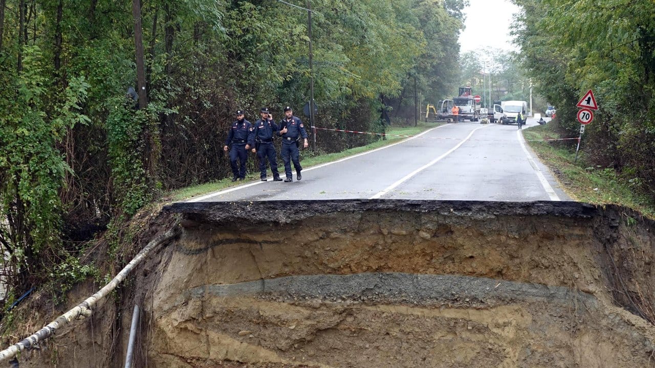Carabinieri begutachten eine durch heftige Regenfälle zerstörte Straße.