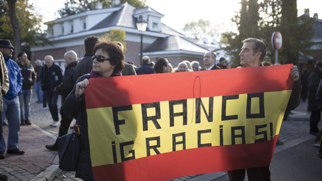 Gegner der Umbettung tragen eine spanische Flagge mit der Aufschrift "Franco Danke".