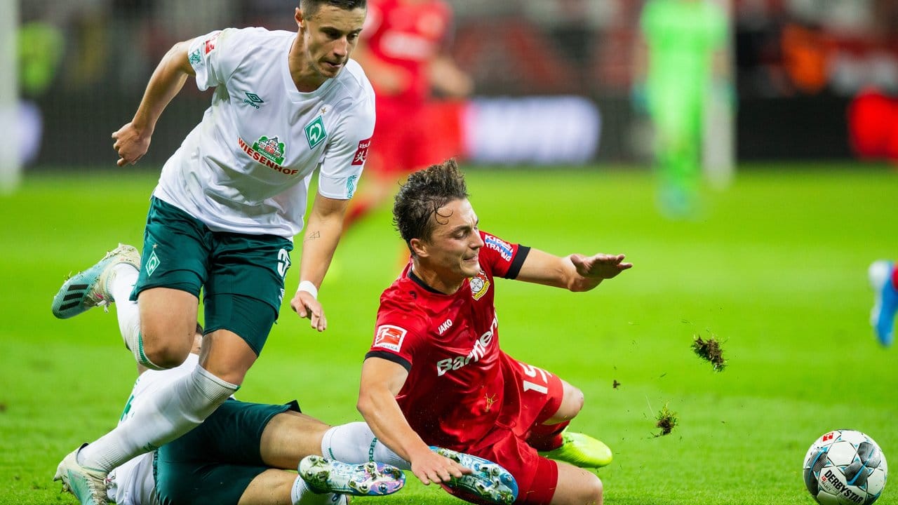 Leverkusens Julian Baumgartlinger (r) wird von Bremens Milot Rashica zu Fall gebracht, links läuft Bremens Marco Friedl.