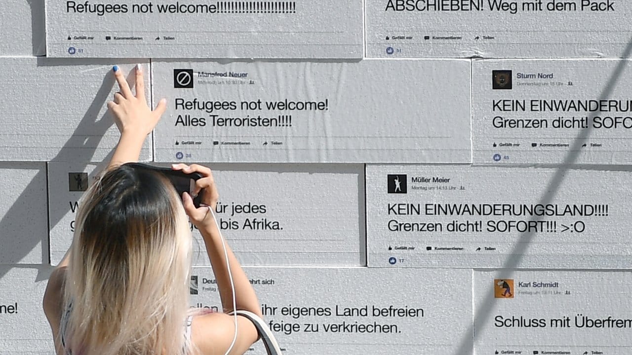 Eine Frau schaut sich auf dem Berliner Gendarmenmarkt eine Mauer an, auf die sogenannte "hate speech" gedruckt ist.