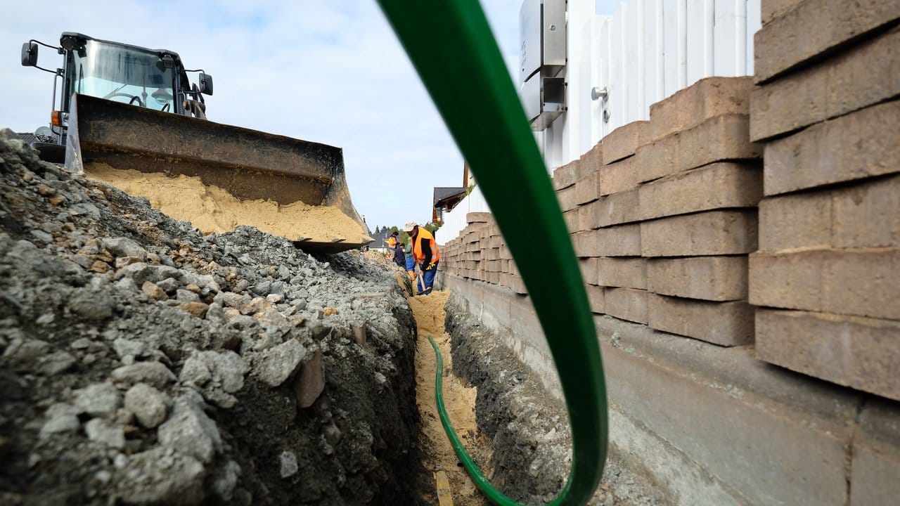 Bauarbeiter bereiten die Verlegung von Glasfaserkabeln in einem Wohngebiet vor.