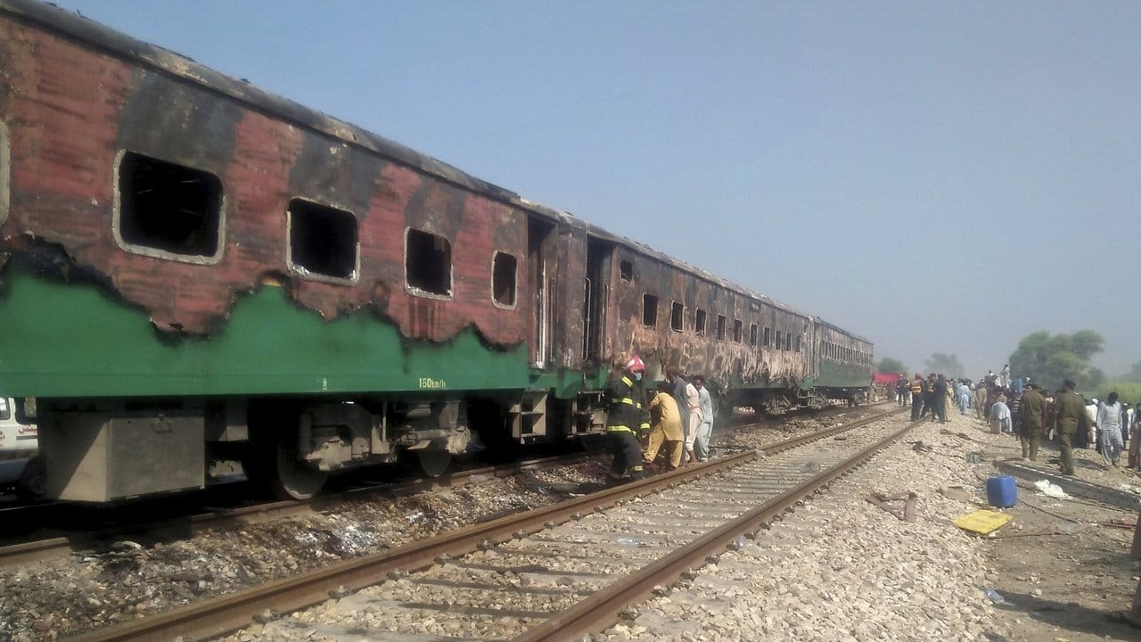 Pakistanische Beamte untersuchen den Zug nach dem Brand.