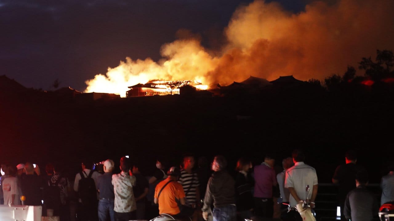 Menschen beobachten den Brand der historischen Shuri Burg.