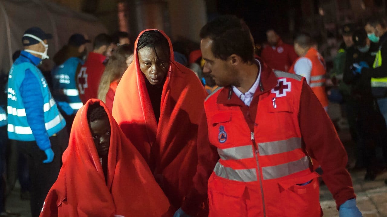 Afrikanische Migranten, die aus einem Schlauchboot im Mittelmeer gerettet wurden, werden von Helfern im Hafen von Malaga empfangen.
