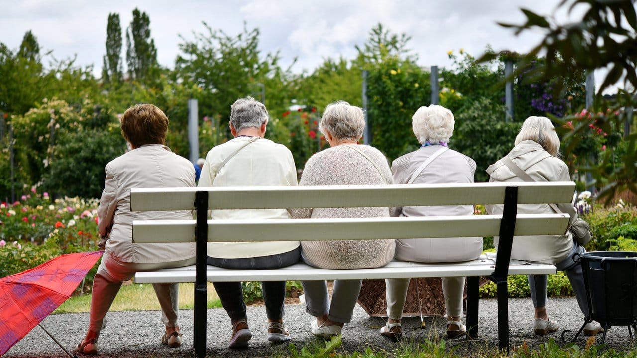 Fünf ältere Frauen machen nach einem Regenschauer eine Pause auf einer Parkbank.