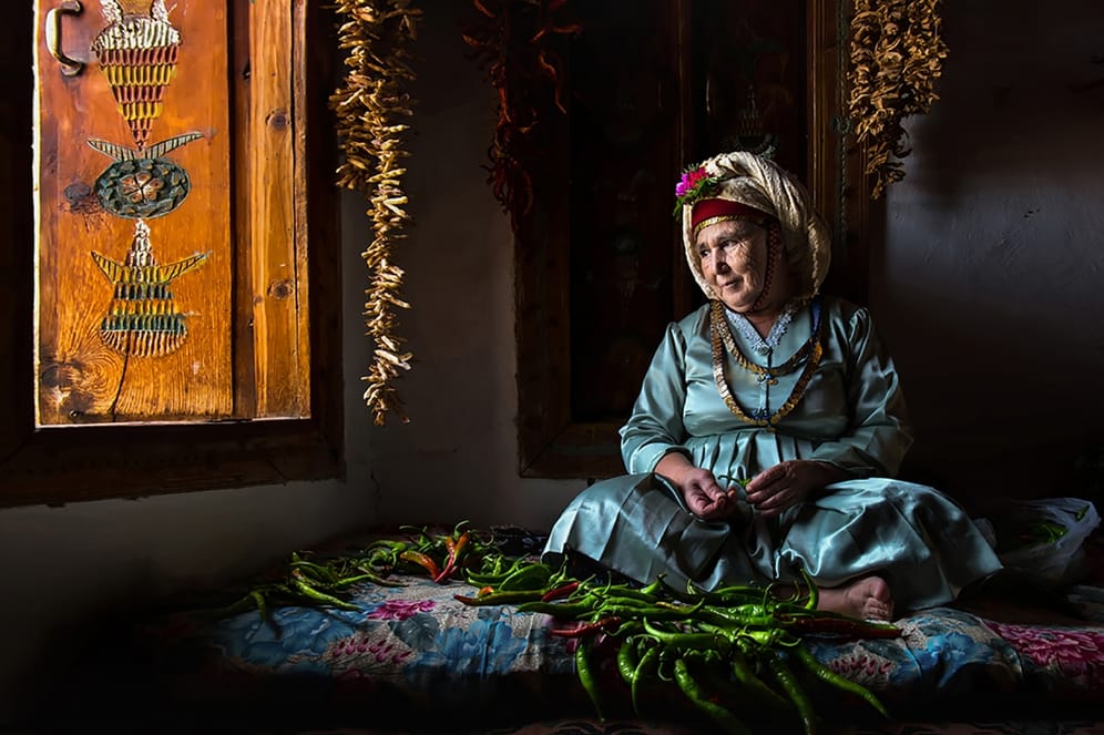 Frau, die das traditionelle, türkische Seidenkopftuch mit frischen Blumen trägt: Çomakdağ ist ein kleines türkisches Dorf, in dem noch starke kulturelle Traditionen lebendig sind.