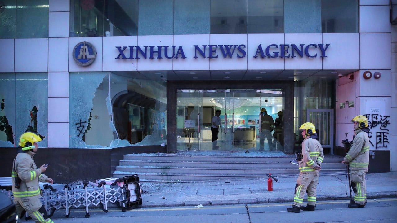 Einsatzkräfte der Feuerwehr stehen vor dem Gebäude der chinesischen Nachrichtenagentur Xinhua in Hongkong, dessen Fenster bei Protesten gegen die Regierung zerstört wurden. Einsatzkräfte der Feuerwehr stehen vor dem Gebäude der chinesischen Nachrichtenagentur Xinhua in Hongkong, dessen Fenster bei Protesten gegen die Regierung zerstört wurden.