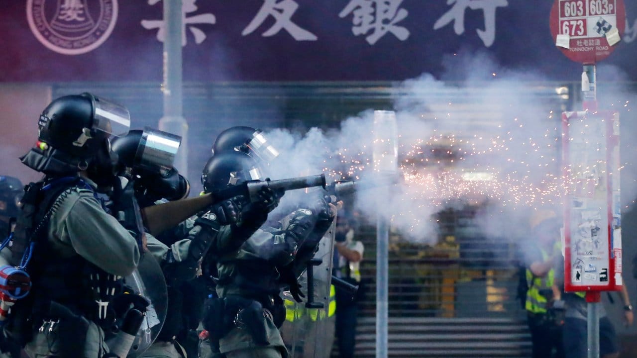 Polizisten mit Gasmasken schießen Tränengas auf Demonstranten. Polizisten mit Gasmasken schießen Tränengas auf Demonstranten.