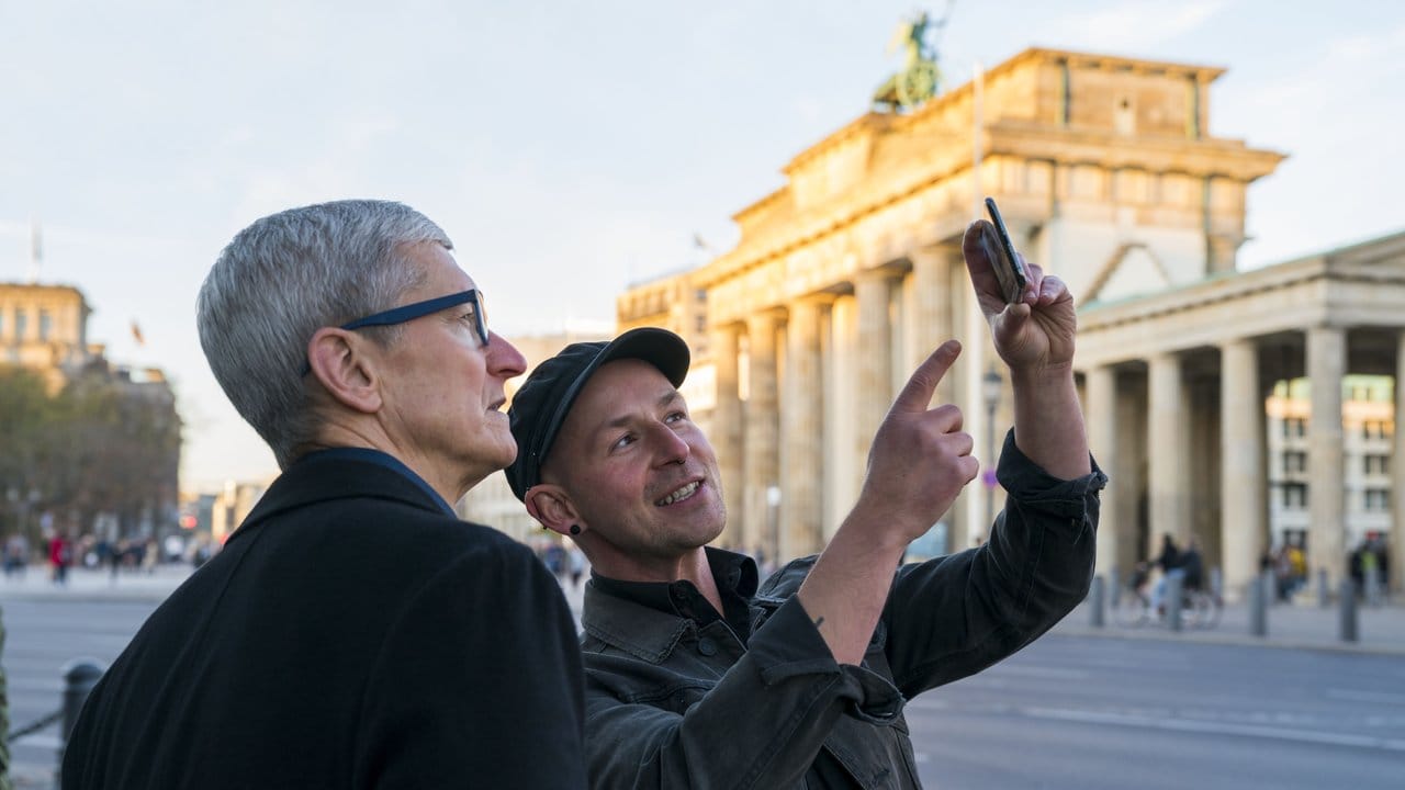 Apple-Chef Tim Cook (l) lässt sich am Brandenburger Tor von Entwickler Peter Kolski das Projekt "MauAR" erklären.