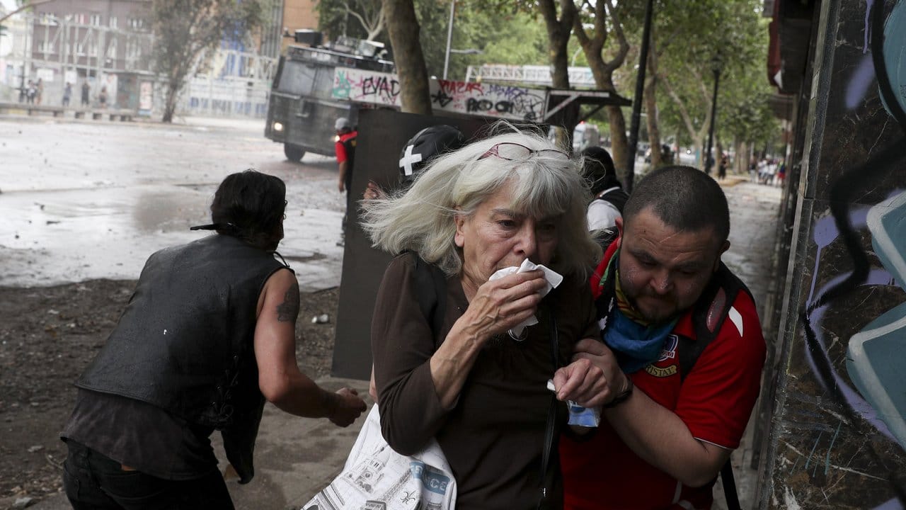 Flucht vor dem Tränengas: Angesichts der gewalttätigen Ausschreitungen in Chile hat Präsident Piñera den Nationalen Sicherheitsrat einberufen.