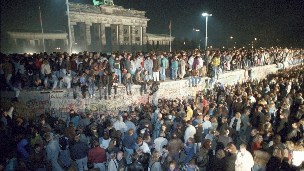 Menschen feiern auf der Berliner Mauer in der Nacht vom 9.