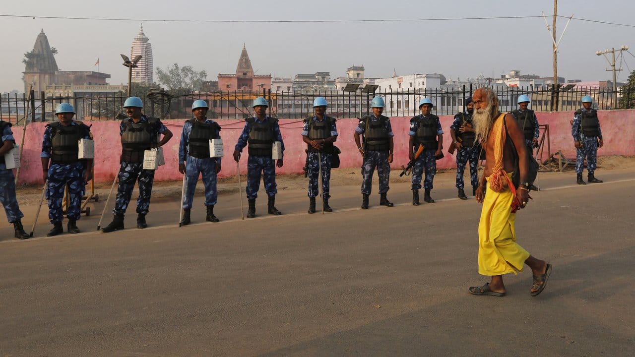 Ein Sadhu - ein hinduistischer Heiliger - geht in Ayodhya an Sicherheitsoffizieren vorbei.