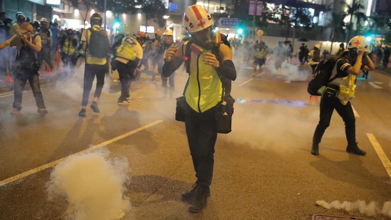 Ein Sanitäter unter den Demonstranten reagiert trotz Atemmaske auf das Tränengas der Polizei.