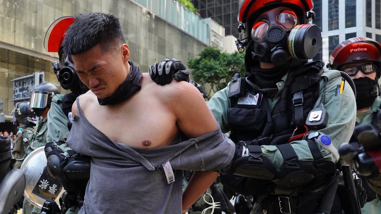 Polizisten nehmen in martialischer Ausrüstung einen Demonstranten fest.