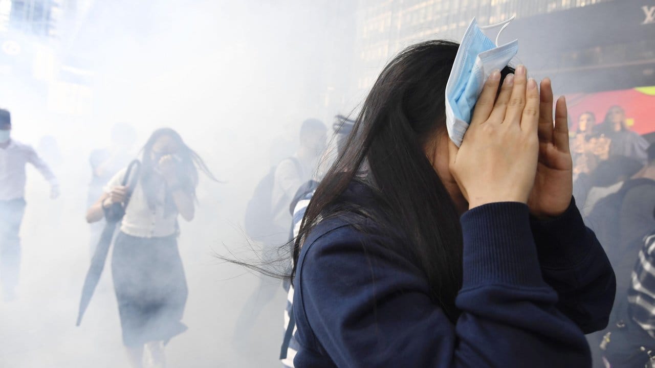 Eine Demonstrantin versucht sich vor dem von der Polizei eingesetzten Tränengas zu schützen.