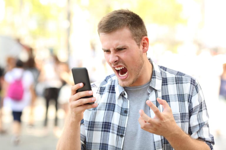 Ein Mann schaut wütend auf sein Smartphone