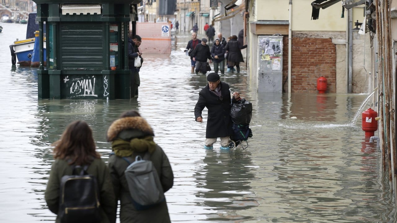 Menschen waten durch eine überflutete Straße.