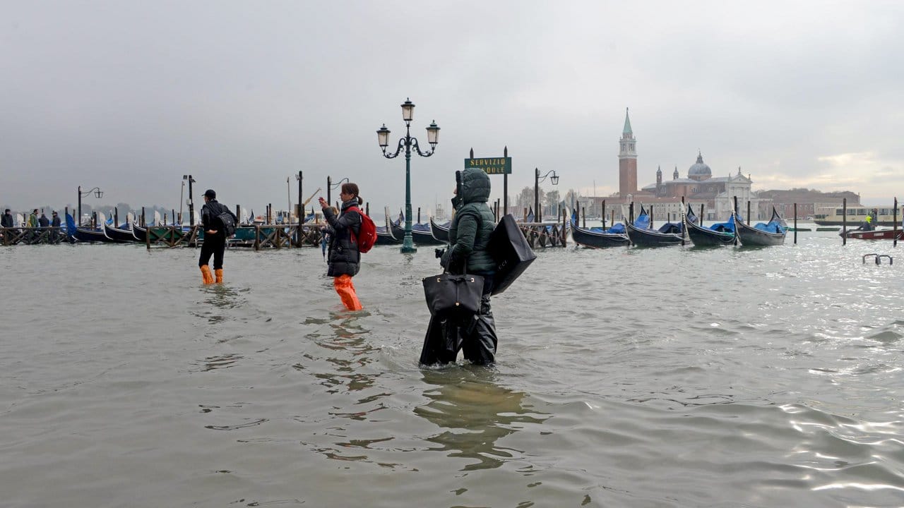 Immer auf den Wegen bleiben: Menschen waten unweit des Ufers zum "Bacino San Marco" durchs überflutete Venedig.