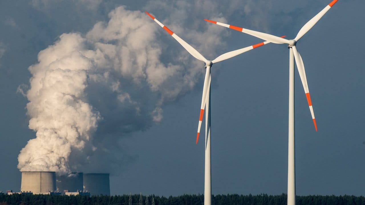 Windräder drehen sich vor den Kühltürmen des Braunkohlekraftwerkes in Jänschwalde (Brandenburg).