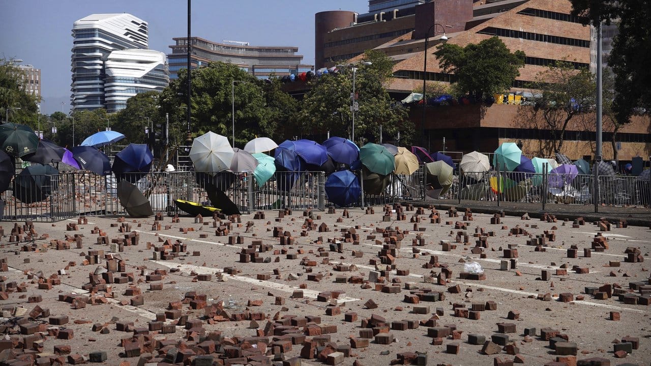 Auf einer Straße vor einer Barrikade, die von Demonstranten der Polytechnischen Universität Hongkong gebaut wurde, sind Ziegelsteine verstreut.