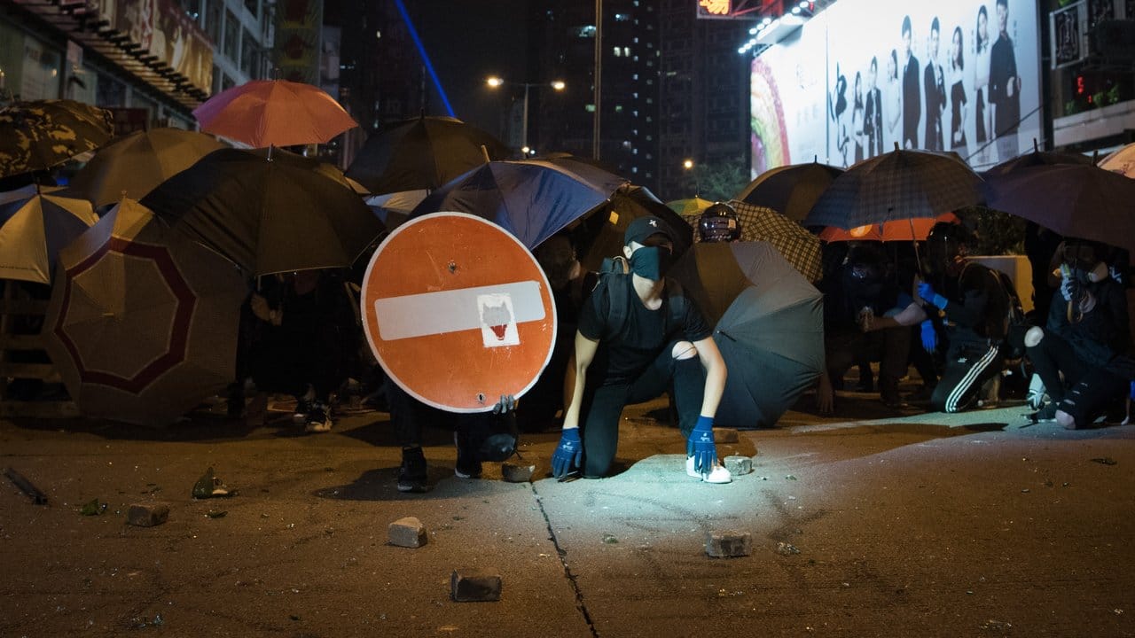 Demonstranten bilden hinter Regenschirmen gegen die Polizei eine Barrikade.