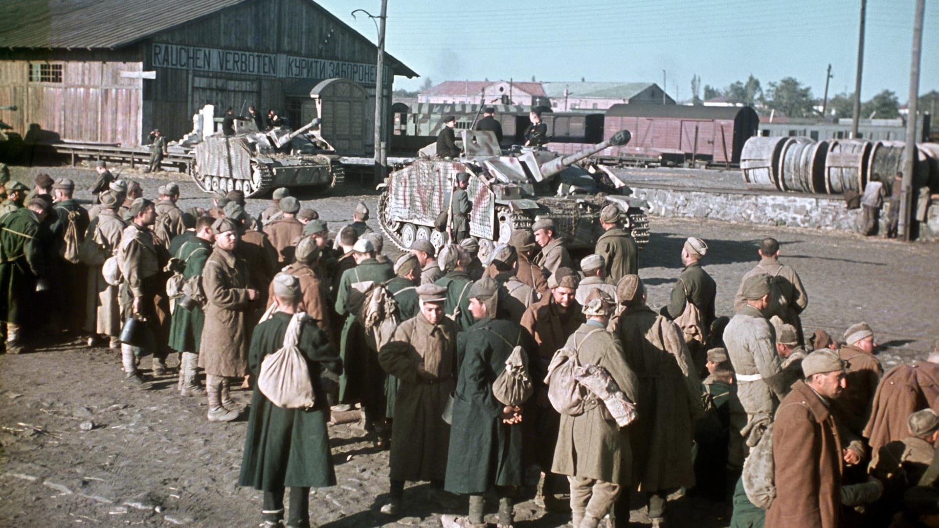 Russische Kriegsgefangene in der Ukraine, bewacht von deutschen Panzern, warten auf ihren Abtransport im Jahre 1943.