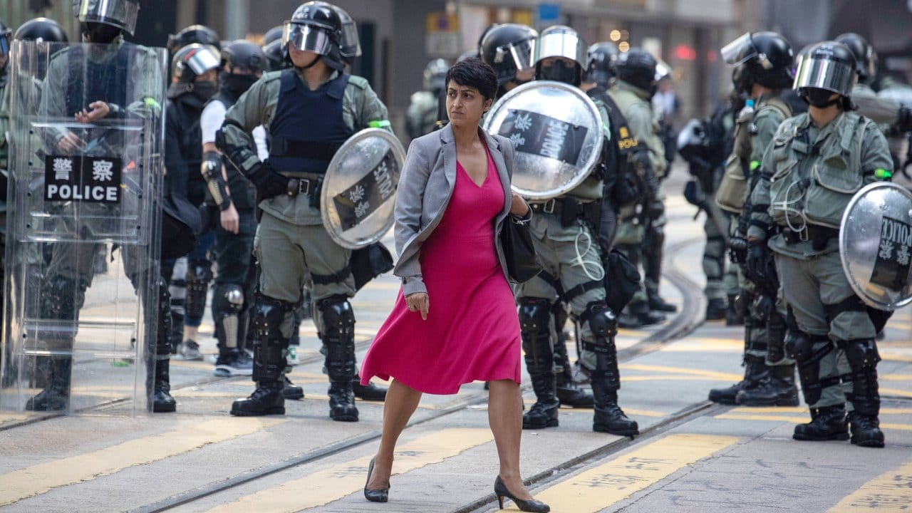 Alltag in Hongkong: Eine Frau geht an Polizisten vorbei, die eine Straße sichern.