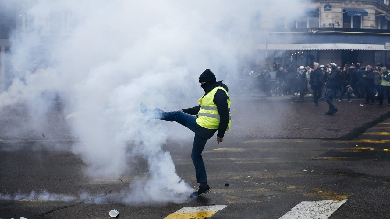 Ein Demonstrant tritt einen Tränengasbehälter von sich weg.
