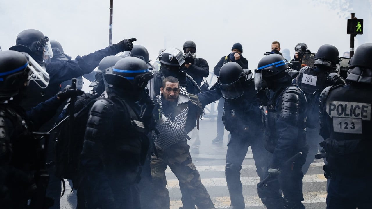 Ein Demonstrant wird in Paris von Polizisten festgehalten.