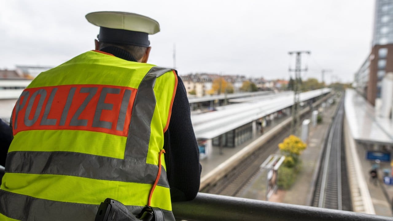 Ein Bundespolizist steht am Hauptbahnhof auf einer Brücke und beobachtet die Bahngleise.