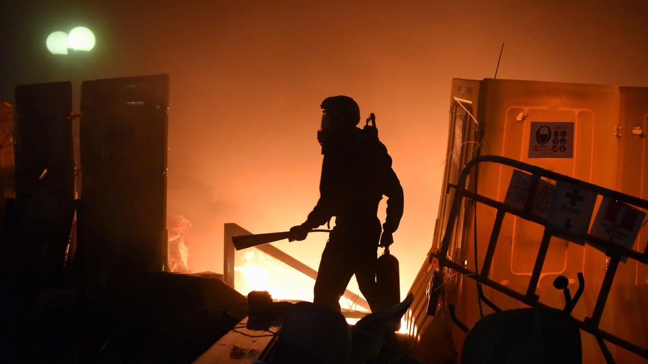 Ein Demonstrant geht in den frühen Morgenstunden im Schein eines Feuers mit einem Feuerlöscher über den Campus der Polytechnischen Universität.