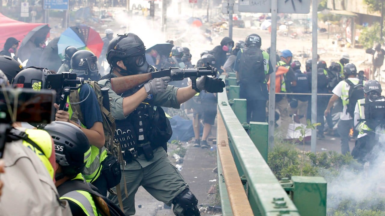 Ein Bereitschaftspolizist legt sein Gewehr an, um Tränengas abzufeuern.