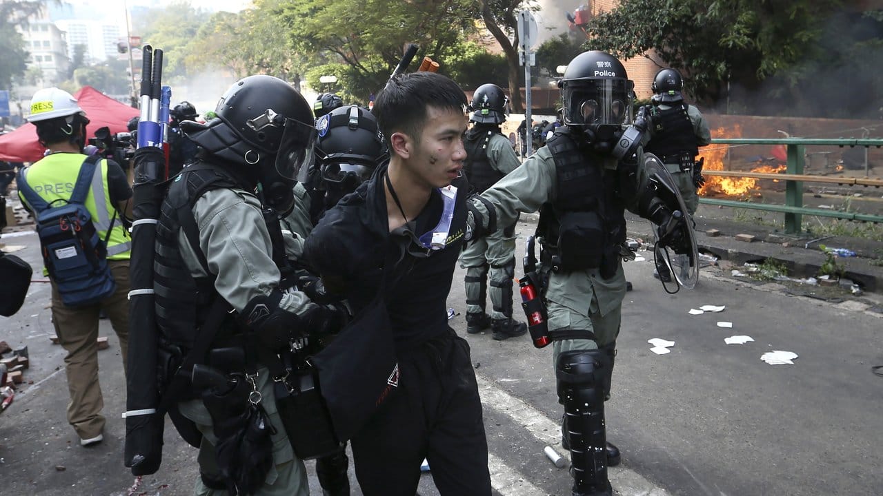 Polizisten nehmen einen Demonstranten fest.