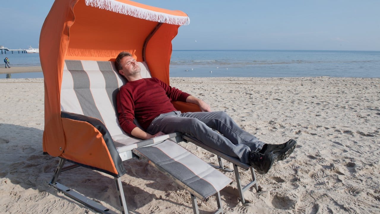 Jan Müller, Geschäftsführer der Strandkorbfabrik Heringsdorf, liegt am Strand auf der Insel Usedom in einem faltbaren Strandkorb.