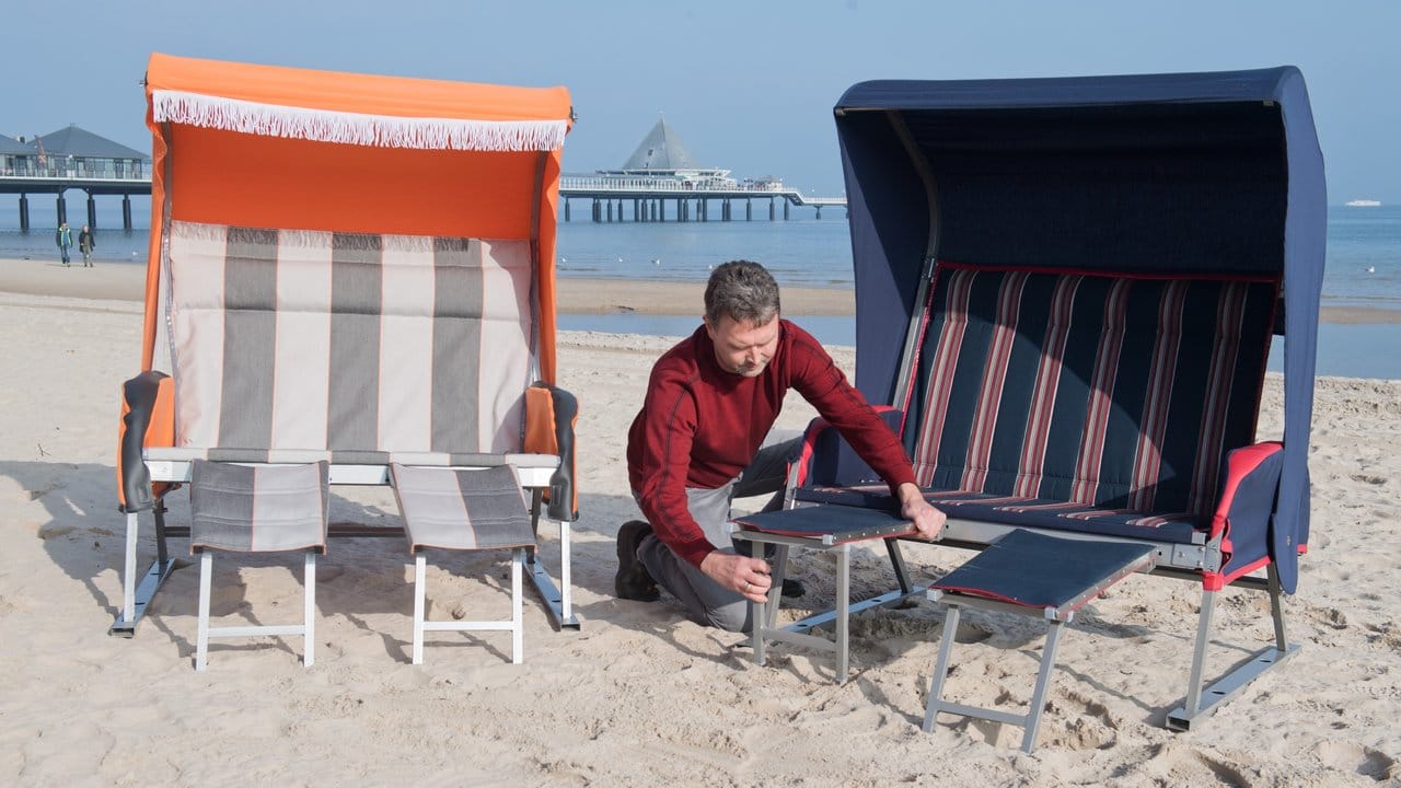 Jan Müller, Geschäftsführer der Strandkorbfabrik Heringsdorf, baut am Strand auf der Insel Usedom einen faltbaren Strandkorb auf.